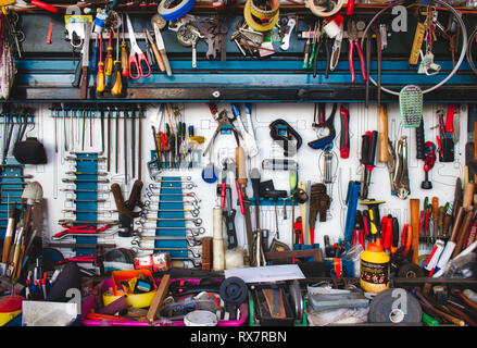 A collection of assorted tools hanging on the wall with a work bench in a garage Stock Photo