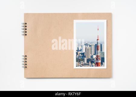 Travel and design concept - Top view of kraft notebook, white frame with tokyo travel photo and pen isolated on white background for mockup Stock Photo
