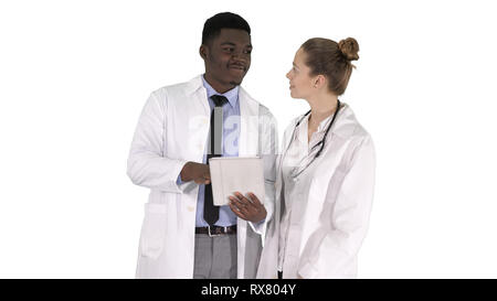 Medium shot. Intellectual healthcare professional afro american doctor with collegue using digital tablet on white background. Professional shot in 4K Stock Photo
