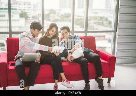 Group of friends sitting on sofa using laptop and smartphone technology Stock Photo