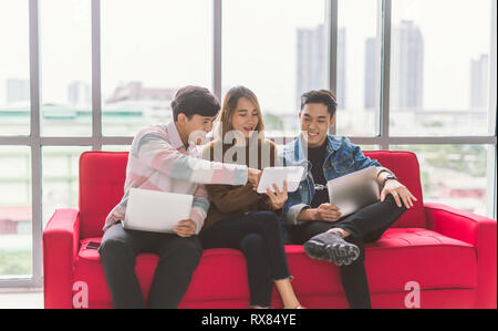 Group of friends sitting on sofa using laptop and smartphone technology Stock Photo