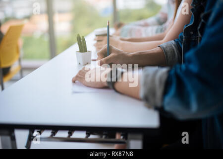 Closeup of hands students sitting on lecture and having test holding pencil writing on paper answer sheet .Testing education training university learn Stock Photo