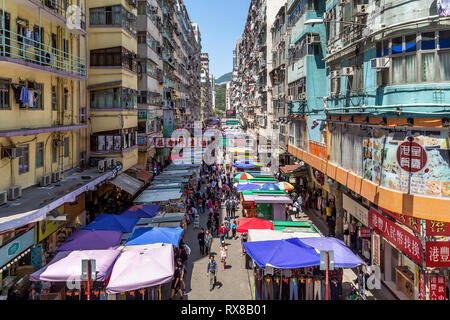 Laundry hangs out to dry from apartment windows above shoppers in a bustling street market. Fa Yuen Street, Mongkok, Kowloon, Hong Kong, China. Stock Photo