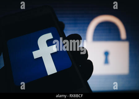 Facebook icon, logo is shown on smartphone display, open lock, numbers zero, one as a texture, blue gradient unfocused on background Stock Photo