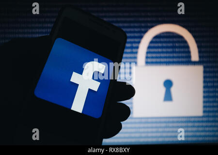 Facebook icon, logo is shown on smartphone display, open lock, numbers zero, one as a texture, blue gradient unfocused on background Stock Photo