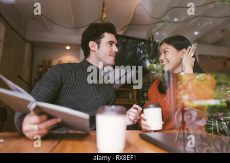 Happy Asian girl and friends chatting talking at the coffee shop cafe in university keep eye contact and laughing together, Stock Photo