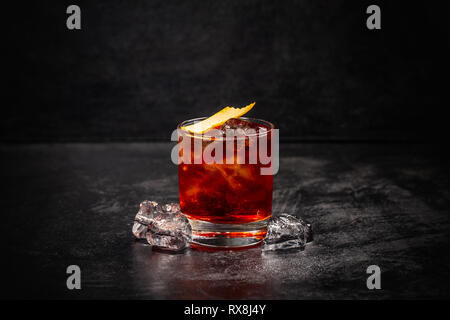 Glass of Negroni cocktail decorated with orange peel on dark background Stock Photo