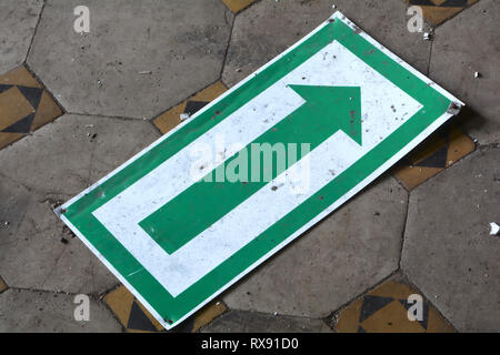 old sign with directional arrow on the floor of an abandoned factory Stock Photo