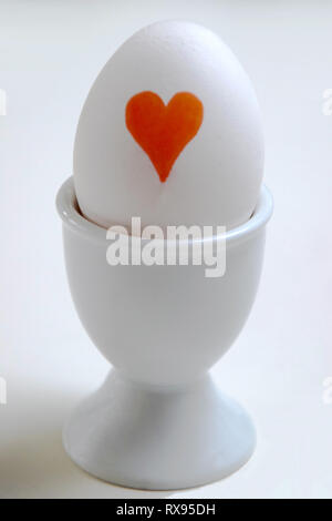 Red heart painted on white egg in an egg cup Stock Photo