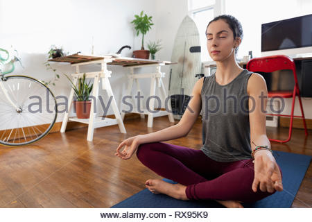 Serene young Latinx woman meditating on yoga mat