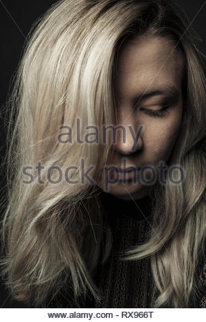 Close up portrait beautiful young woman with blonde hair looking down Close up portrait beautiful young woman with blonde hair looking down