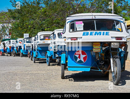 Puerto Princesa City, Palawan, Philippines: Blue and white tricycles waiting in line for tourists in front of the airport Stock Photo