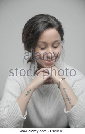 Portrait confident serene beautiful young Jamaican woman with tattoos and eyes closed