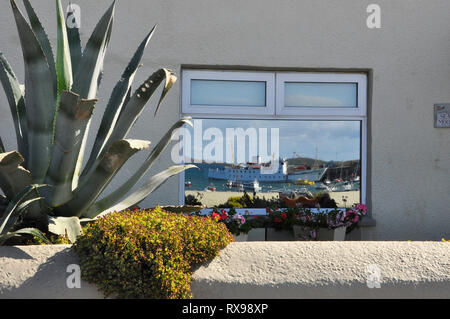 Sciillonian 3 reflected in the window of a cottage on the Strand in Hugh Town, St Mary's, Isles of Scilly. Stock Photo