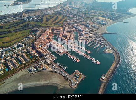 Aerial drone point view panorama of Almerimar townscape, greenhouses,  moored nautical vessels in the harbor, coastline sandy beach, Spain Stock Photo