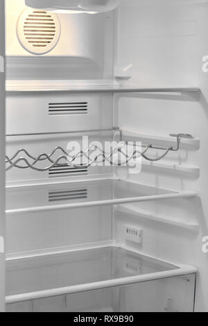 Open door of modern refrigerator with empty shelves and bottle rack, white color vertical view Stock Photo