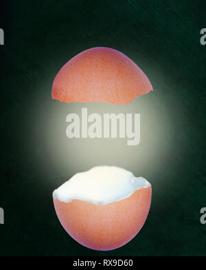 Broken chicken eggshell with glow isolated on chalkboard background with copy space. Stock Photo