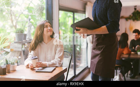 Young Asian woman making order at restaurant Stock Photo