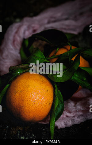 High angle view of tangerines with leaves and fabric on table Stock Photo