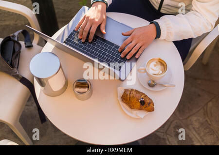 Midsection of man with breakfast on table using laptop while sitting at sidewalk cafe Stock Photo