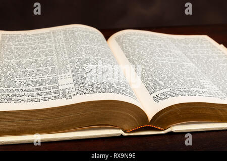 Horizontal close-up shot of an old Bible lying open on a brown background. Stock Photo