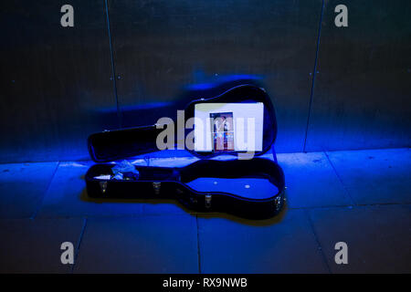 A buskers guitar case lies open in blue neon light in an underpass lochaber fort william scottish highlands uk Stock Photo