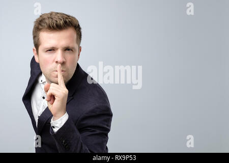 Handsome man in suit making silence gesture. Keep it in secret. Stock Photo
