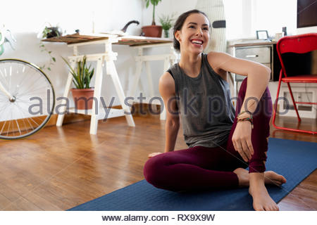 Happy young Latinx woman practicing yoga at home