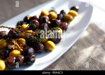 Close-up of olives with herbs served in plate on table Stock Photo