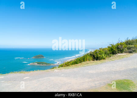 Summit track and beaches and sea stretching to horizon below viewed from summit of Mount Maunganui. Stock Photo