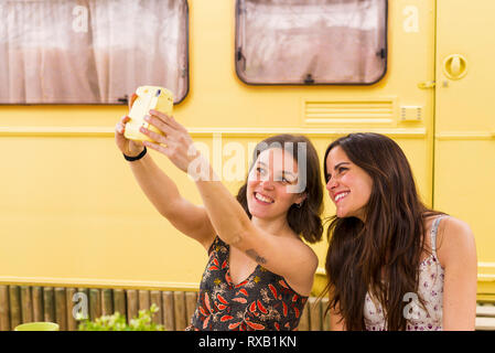 Happy female friends taking selfie with instant camera against motor home at backyard Stock Photo