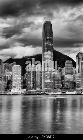 The tallest skyscraper tower on Hong Kong cityscape in Central CBD district against the tallest mountain on a cloudy morning when lights reflect in bl Stock Photo