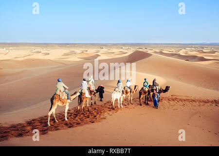 Tourists enjoying with camel caravan in the Sahara desert. Erg Chebbi, Merzouga, Morocco. Stock Photo