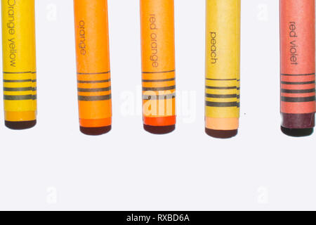 Wax crayons on a white background, orange yellow, orange, red orange, peach and red violet crayons with the name of the color on the crayons Stock Photo