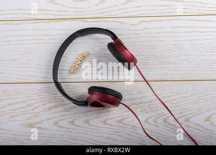 Dice-sized alphabet cubes spelling music and red headphones on wooden background Stock Photo