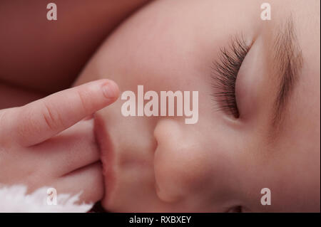 Close up of baby girl face with hand in mouth Stock Photo