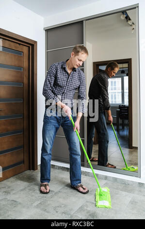 The man cleans the room. He washes the floor using a mop. Stock Photo