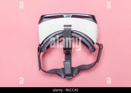 Minimal simple flat lay with virtual reality VR glasses helmet headset on pink pastel trendy background. Smartphone using with virtual reality goggles Stock Photo