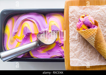 Multicolored pink, blue and purple gum flavor ice cream in metallic form next to a ready riped cone Stock Photo