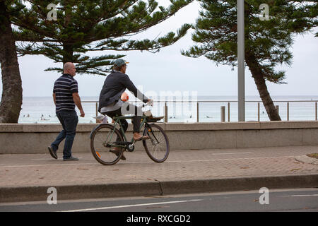 Man riding his bicycle beside Manly beach in Sydney,Australia Stock Photo