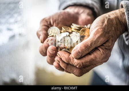 Pensioner man holding in hands euro coins. Theme of low pensions Stock Photo