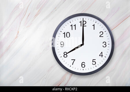Wall clock show eight o'clock on marble texture. Office clock show 8pm or 8am Stock Photo