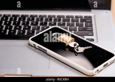 Smartphone and padlock is lying on a laptop keyboard Stock Photo