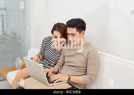Young couple surfing on internet with laptop. Modern white apartment in background Stock Photo