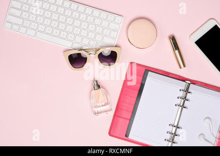 Creative flat lay photo of workspace with cosmetics, coffee, smartphone, glasses,mascara,gloss with copy space on pink background Stock Photo