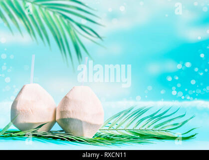 Coconut cocktails in fresh coconuts on palm leaves at sea background. Summer tropical drinks Stock Photo