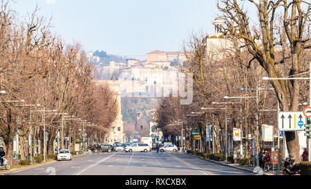 BERGAMO, ITALY - FEBRUARY 19, 2019: people and cars on street Viale Papa Giovanni XXIII and skyline of Upper Town. Bergamo is capital of the Province  Stock Photo