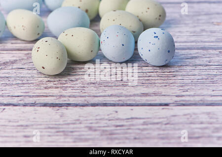 yellow and blue dragee eggs on a white wooden background, macro color photo Stock Photo