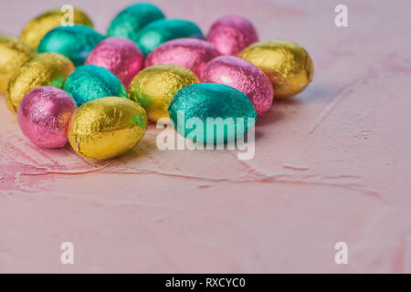 wrapped chocolate eggs on a pink background with copy space Stock Photo