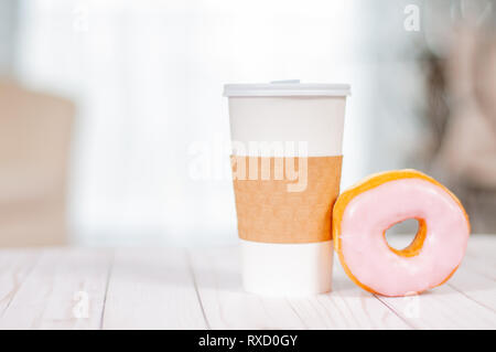 Cup of coffee and chocolate donut on wood table. Coffee break with donuts. Stock Photo